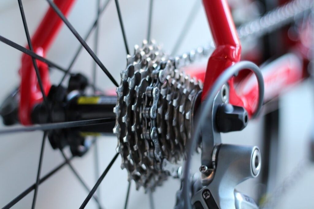 Närbild av cykelns kassett, kedja och bakväxel på ett rött cykelhjul
